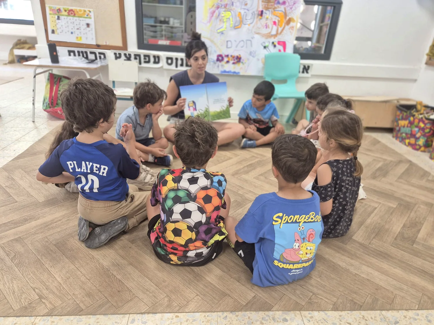 הילדים מקשיבים לסיפור בישיבה על הרצפה