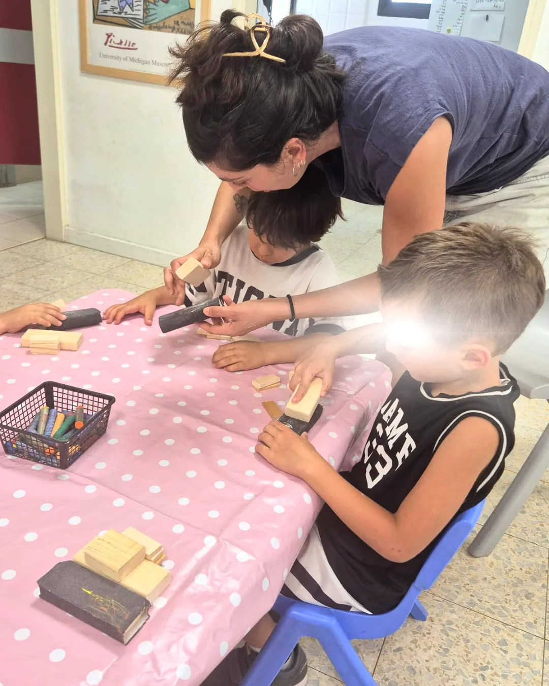 נופר מדריכה ילדים בשיוף חלקי עץ